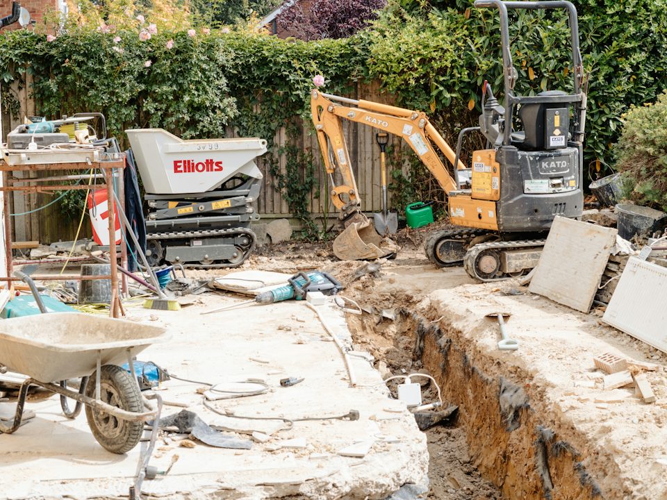 A mini excavator and a trench dug in a backyard