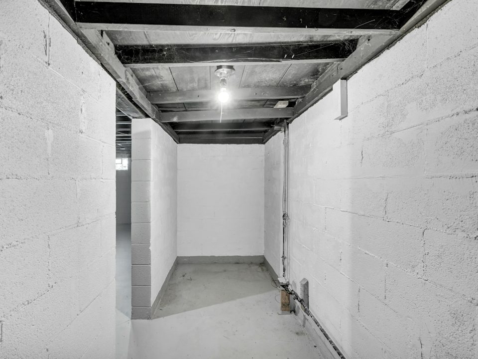 A narrow basement with white painted concrete block walls