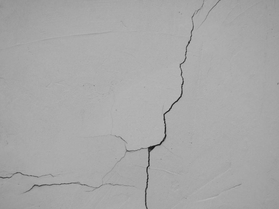 A thin crack running down a grey concrete wall
