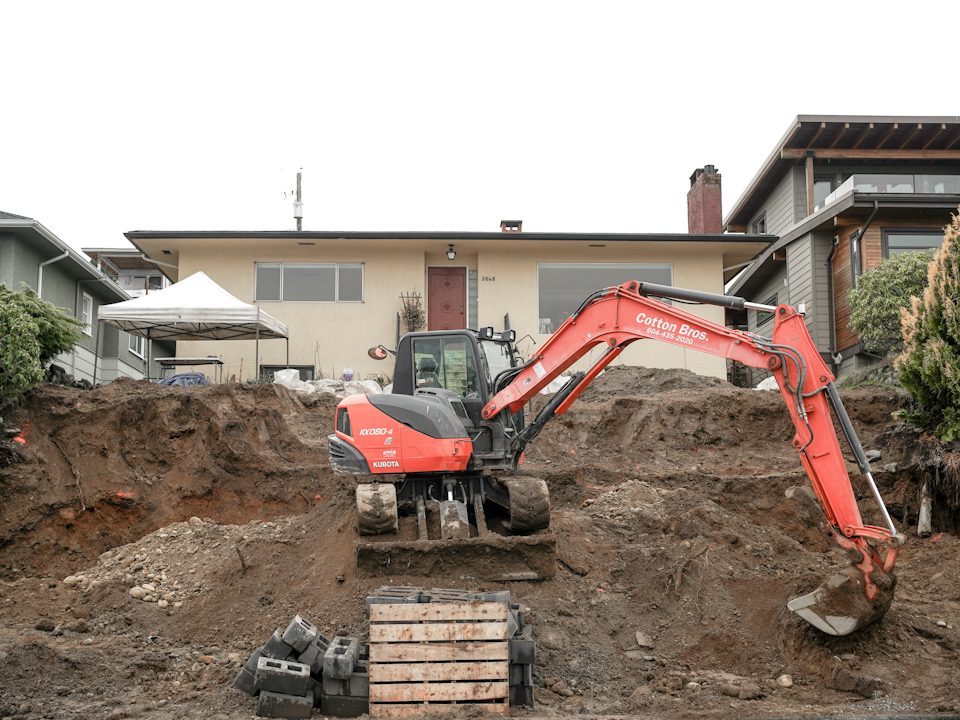 An excavator digging beside a house