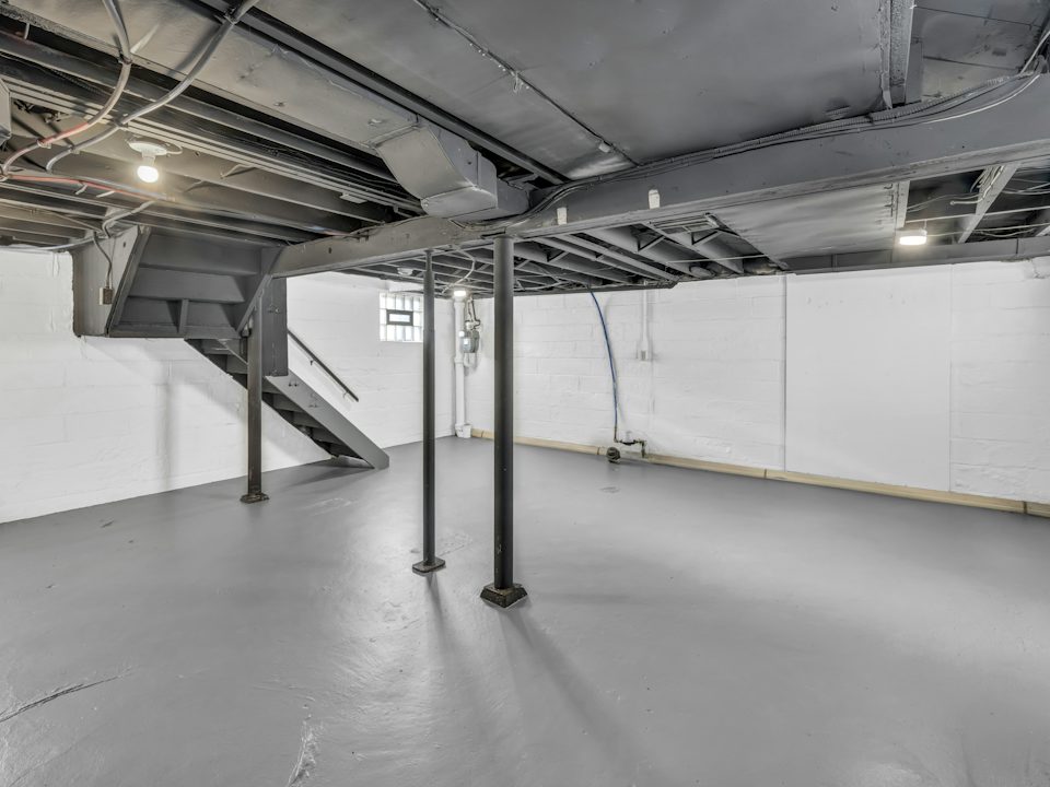 An unfinished basement with exposed joists and support posts