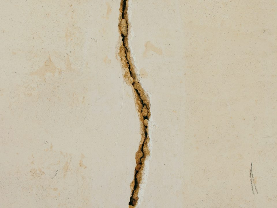 A wide, jagged crack through a concrete surface